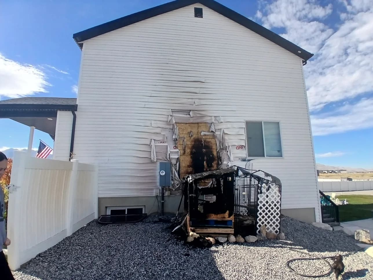 Home exterior with damaged siding removed and restoration equipment staged alongside the house