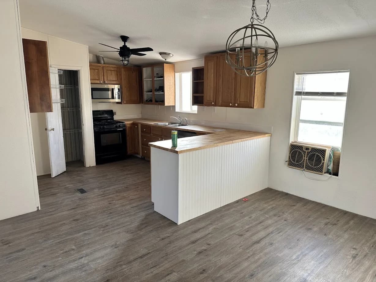 The same kitchen after restoration with new wood cabinetry, a white island and new flooring
