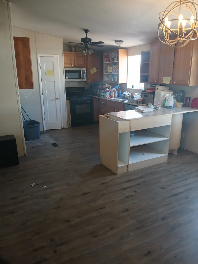 Dated kitchen with damaged cabinets and worn flooring before restoration work began