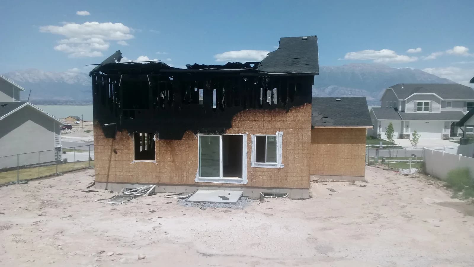 Exterior of a Utah home with the second story burned out and sheathing exposed after a house fire